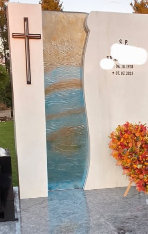 Szkło transparentne z niebieskimi i bursztynowymi smugami koloru i delikatnymi prążkami w poprzek, obsadzone w płycie napisowej